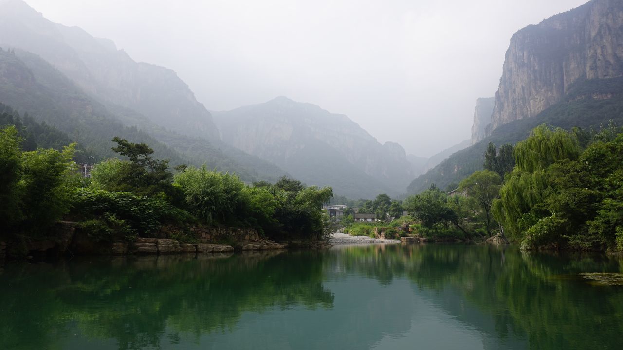 water, mountain, tranquil scene, scenics, tranquility, beauty in nature, tree, waterfront, lake, reflection, nature, majestic, non-urban scene, idyllic, fog, remote, mountain range, sky, foggy, calm, growth, green, day, countryside, tourism, solitude, green color, mist, valley