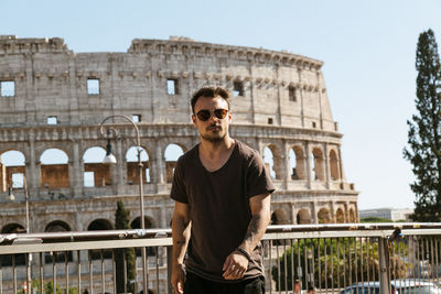 Portrait of young man standing against building