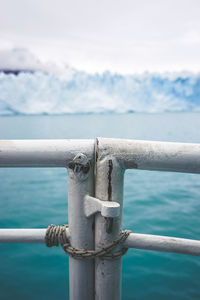 Close-up of metal gate against sea