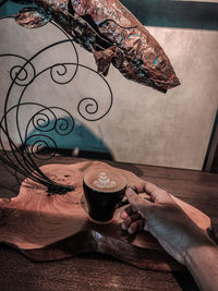 Hand holding coffee cup on table