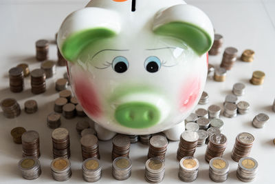 High angle view of piggy bank over coins on table