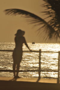 Silhouette man standing on beach against sky during sunset