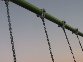 Low angle view of chains hanging against sky during sunset
