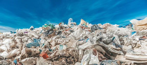 Stack of garbage by sea against blue sky