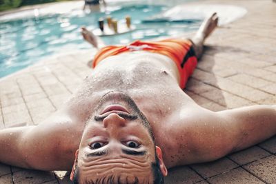 Portrait of shirtless man lying in swimming pool