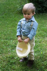 Cute boy holding hat on field