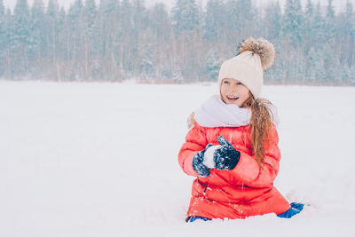 Portrait of smiling young woman standing on snow covered field