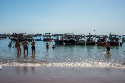 People on beach against clear sky