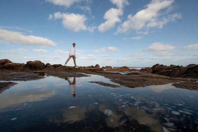 Rear view of man walking on beach against sky