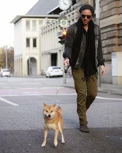 Portrait of man walking with shiba inu on footpath in city