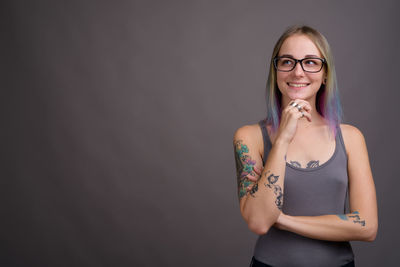 Portrait of smiling young woman standing against wall