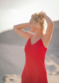 Side view of young woman exercising against wall