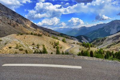 Empty road by mountains against sky