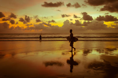 Silhouette man on beach against sky during sunset