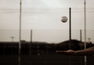 Close-up of hand holding ball hanging on field