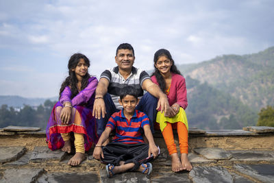 Indian father sitting with his kids smiling while looking into the camera. happy family concept.