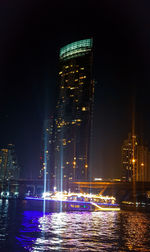 Illuminated modern buildings in city against sky at night