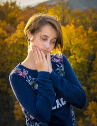 Close-up of young woman against trees during autumn