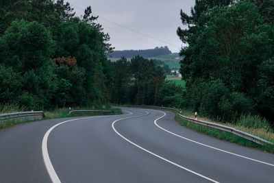 Empty road amidst trees against sky