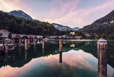 Reflection of wooden posts and houses against mountains at dusk