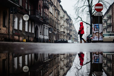 Rear view of woman standing by building in city