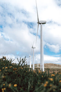 Wind turbines on field against sky