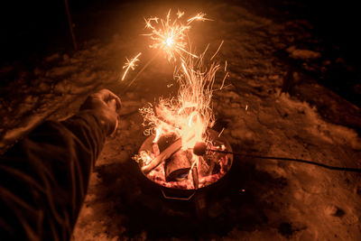 Midsection of man with fire crackers at night