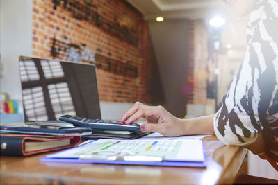 Midsection of woman reading book on table