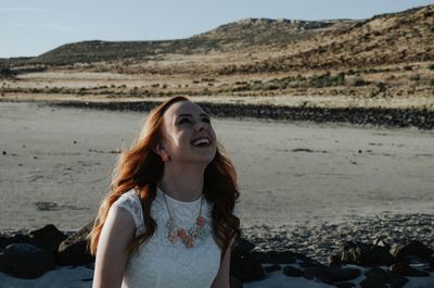 Smiling woman at beach against sky