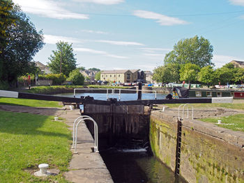 Footpath by canal against sky in city