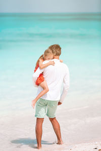 Rear view of father and son standing on beach