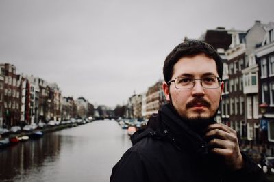 Portrait of man by canal in city