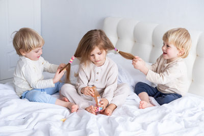 Siblings playing on bed at home