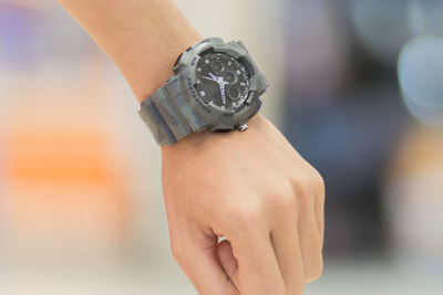 Close-up of hand holding clock against blurred background