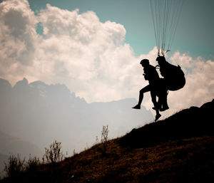 Silhouette man jumping on mountain against sky
