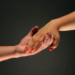 Midsection of couple holding hands against black background