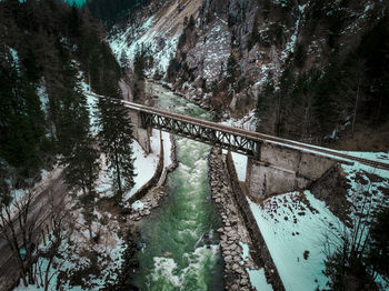 Footbridge over river amidst trees in forest