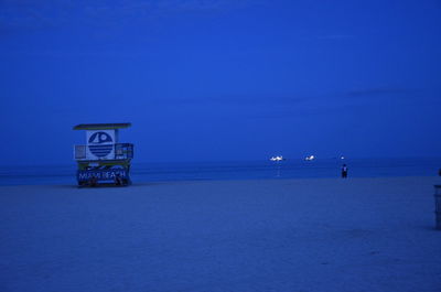 Lifeguard hut on beach against sky at dusk