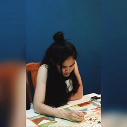 Young woman looking down while sitting on table