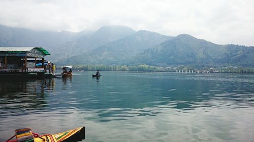Boats in calm lake against mountain range