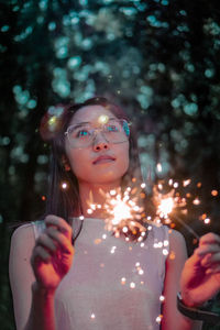 Portrait of woman looking at illuminated tree