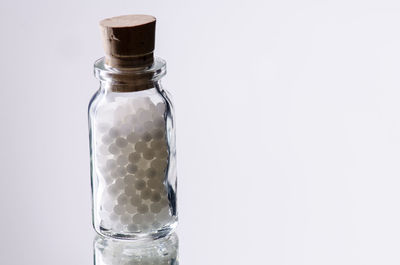 Close-up of bottle in jar against white background