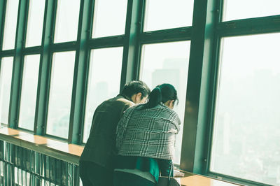 Rear view of friends looking through glass window