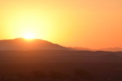 Scenic view of silhouette mountains against orange sky