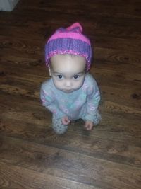 Portrait of cute baby girl lying on hardwood floor