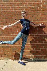 Portrait of young woman standing against brick wall