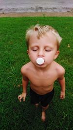 Shirtless boy eating food on field