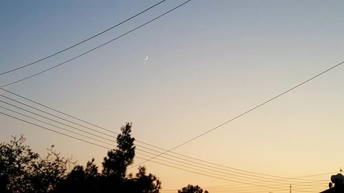 Low angle view of silhouette electricity pylon against sky during sunset