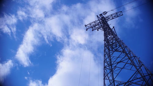 Low angle view of electricity pylon against blue sky