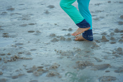 Low section of man walking on beach